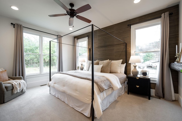 bedroom with ceiling fan, light colored carpet, and multiple windows