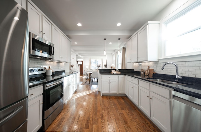 kitchen featuring stainless steel appliances, dark hardwood / wood-style flooring, decorative light fixtures, decorative backsplash, and white cabinets