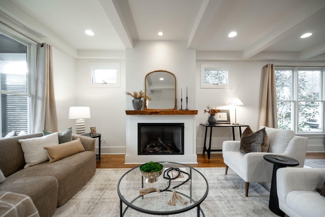 living room featuring plenty of natural light, beamed ceiling, and light hardwood / wood-style floors