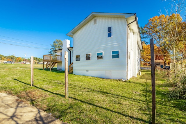 view of side of home featuring a yard and a wooden deck