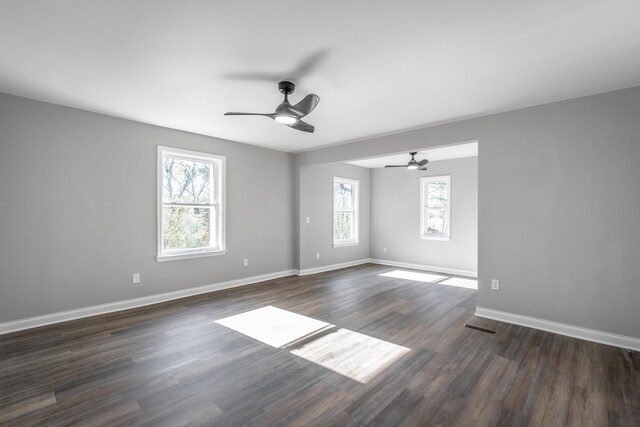 spare room with dark wood-type flooring, ceiling fan, and a healthy amount of sunlight