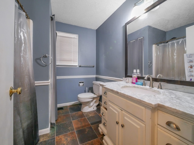 bathroom with vanity, toilet, and a textured ceiling