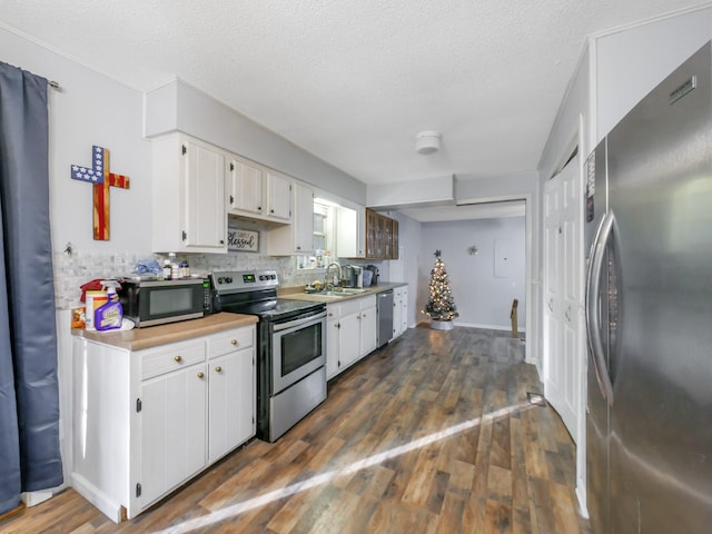 kitchen with white cabinets, a textured ceiling, stainless steel appliances, and dark wood-type flooring