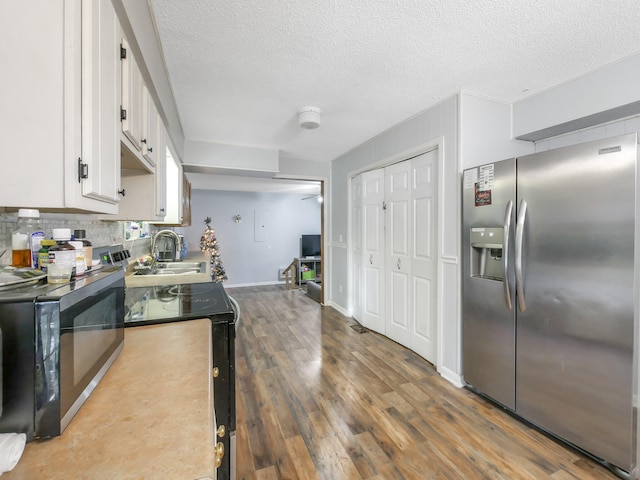 kitchen featuring hardwood / wood-style floors, a textured ceiling, decorative backsplash, white cabinets, and black appliances