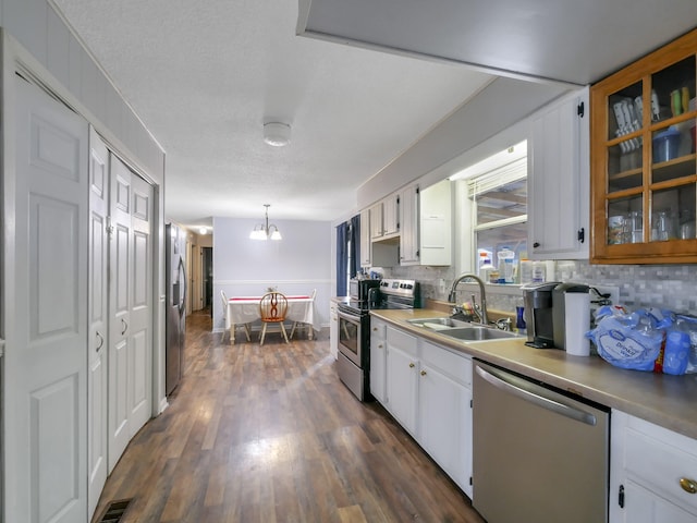 kitchen featuring dark hardwood / wood-style flooring, stainless steel appliances, sink, white cabinets, and hanging light fixtures