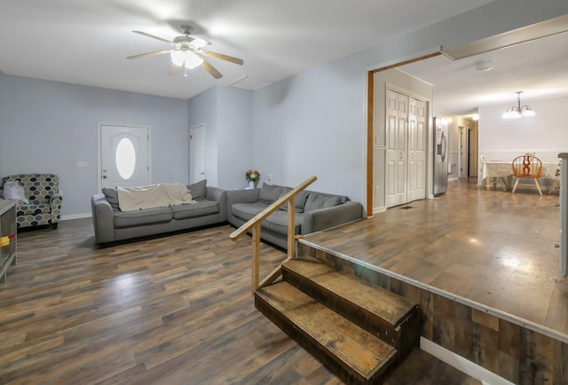 living room featuring ceiling fan with notable chandelier and dark hardwood / wood-style flooring