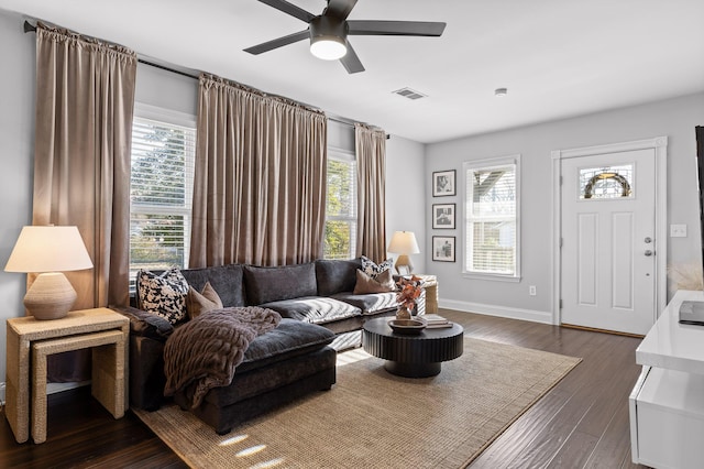 living area with visible vents, baseboards, a ceiling fan, and dark wood-style flooring