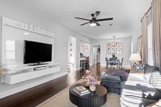 living area with ceiling fan with notable chandelier, wood finished floors, visible vents, and baseboards