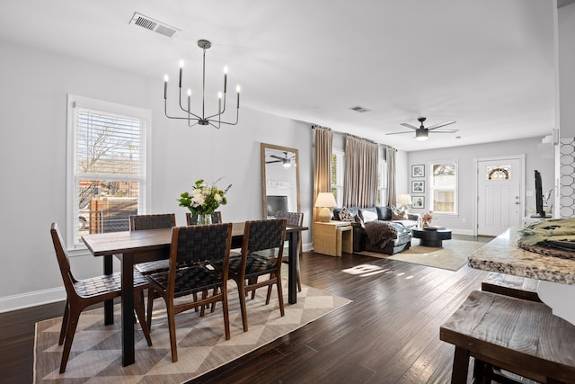 dining room with visible vents, dark wood-type flooring, and ceiling fan with notable chandelier