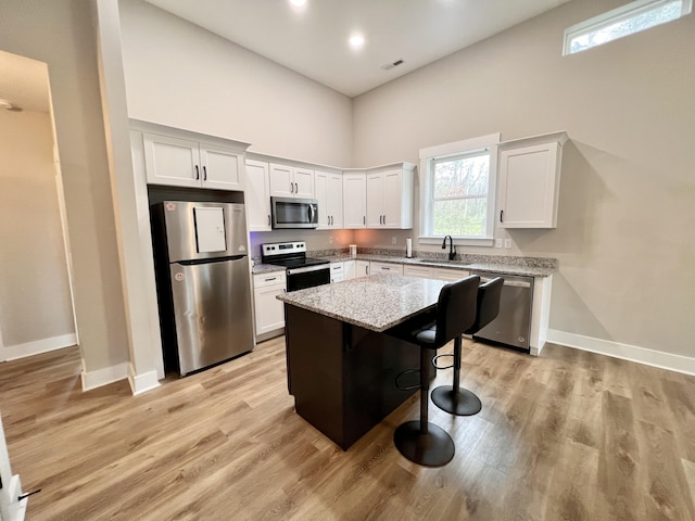 kitchen with white cabinetry, sink, a center island, a kitchen breakfast bar, and appliances with stainless steel finishes