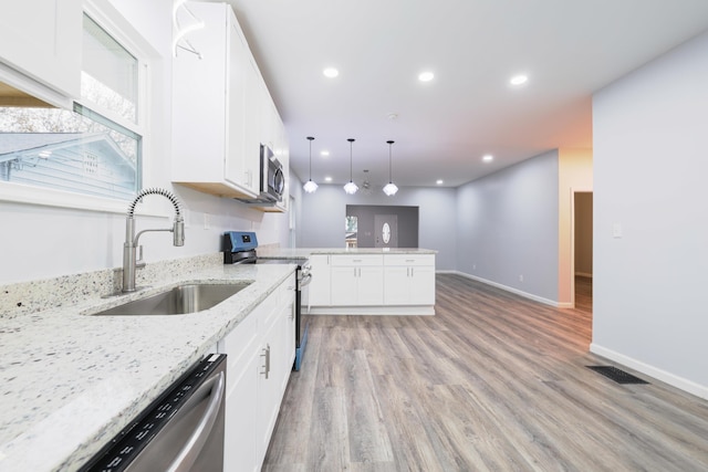 kitchen with white cabinets, appliances with stainless steel finishes, light hardwood / wood-style floors, and sink