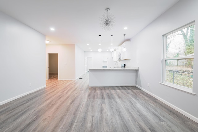 interior space featuring light wood-type flooring, decorative light fixtures, white cabinetry, and sink