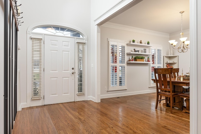 foyer entrance with a healthy amount of sunlight, crown molding, hardwood / wood-style floors, and a chandelier