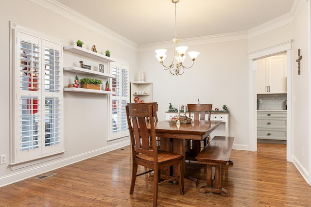 dining space featuring light hardwood / wood-style floors, crown molding, and an inviting chandelier