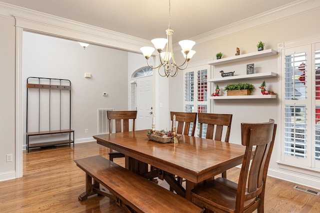 dining area with crown molding, light hardwood / wood-style floors, and a notable chandelier