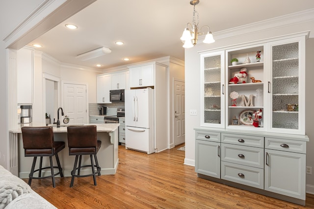 kitchen with gray cabinetry, light hardwood / wood-style flooring, white fridge, a kitchen bar, and white cabinets