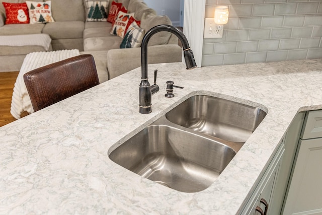 room details featuring green cabinets, light stone counters, and sink