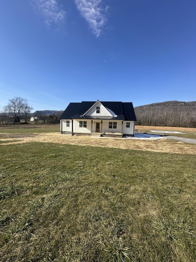 view of front of house with a porch, a mountain view, and a front lawn