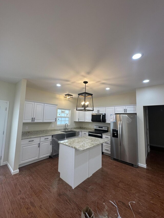 kitchen featuring appliances with stainless steel finishes, hanging light fixtures, a center island, white cabinetry, and an inviting chandelier