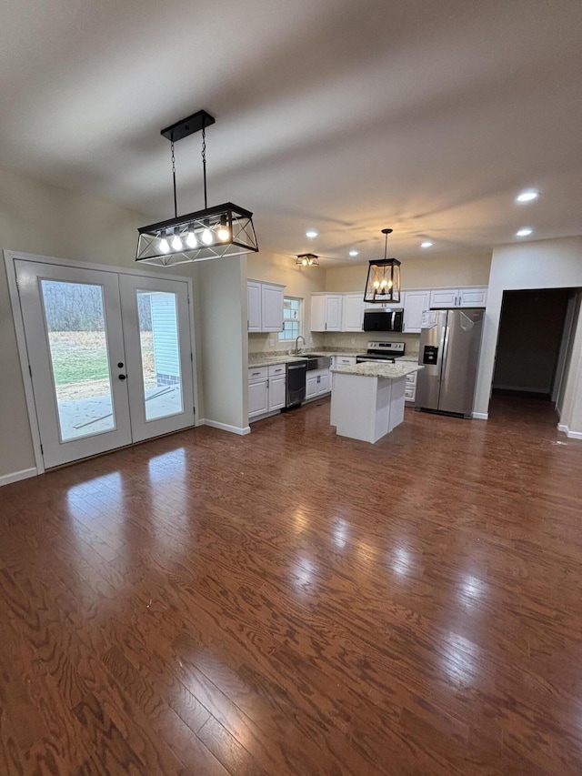 kitchen featuring white cabinetry, open floor plan, hanging light fixtures, appliances with stainless steel finishes, and a center island