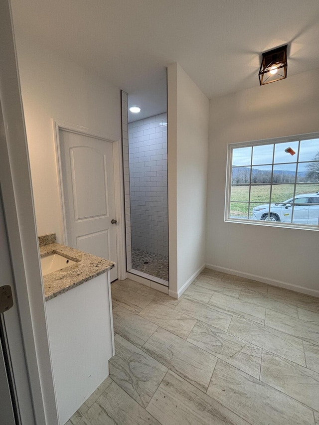 full bath featuring marble finish floor, a shower stall, baseboards, and vanity