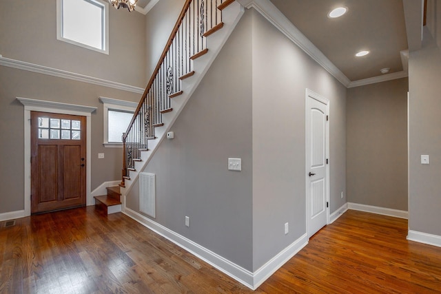 foyer entrance with a chandelier, wood-type flooring, and ornamental molding