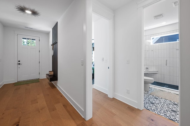 entryway with light hardwood / wood-style flooring and tile walls