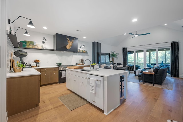 kitchen with a center island with sink, light wood-type flooring, high end stove, and white dishwasher