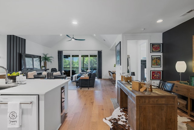 kitchen featuring ceiling fan, dishwashing machine, vaulted ceiling, and light wood-type flooring