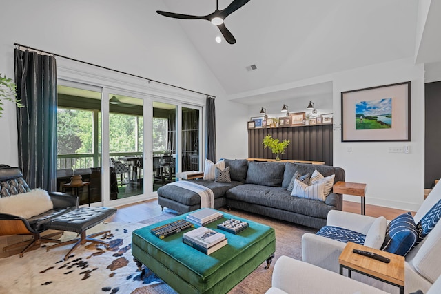 living room with ceiling fan, high vaulted ceiling, and light wood-type flooring