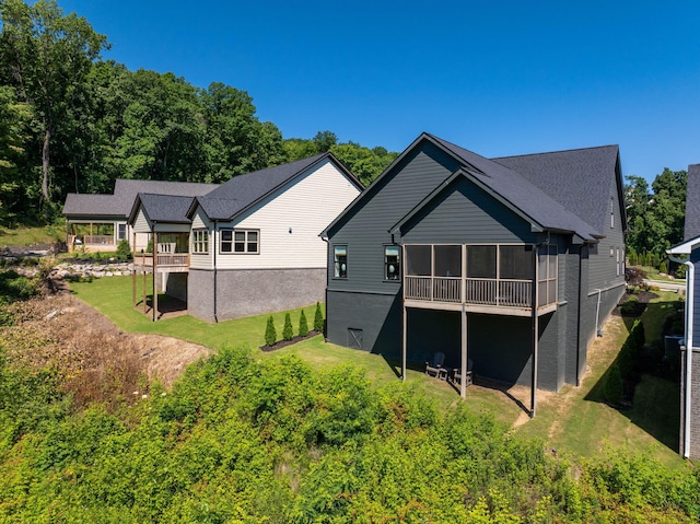 rear view of property with a sunroom and a lawn