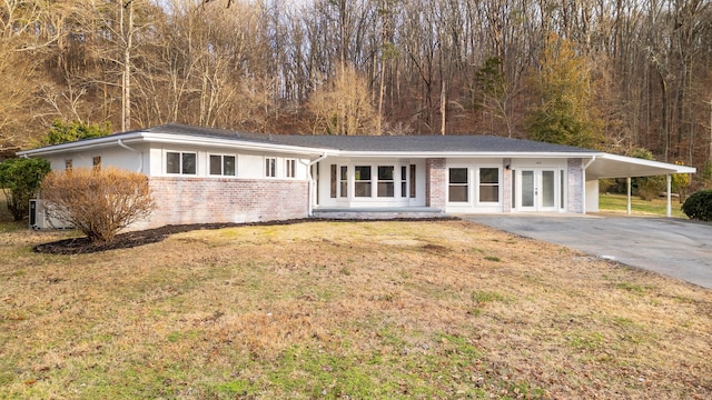 ranch-style house with a front lawn, a carport, and french doors