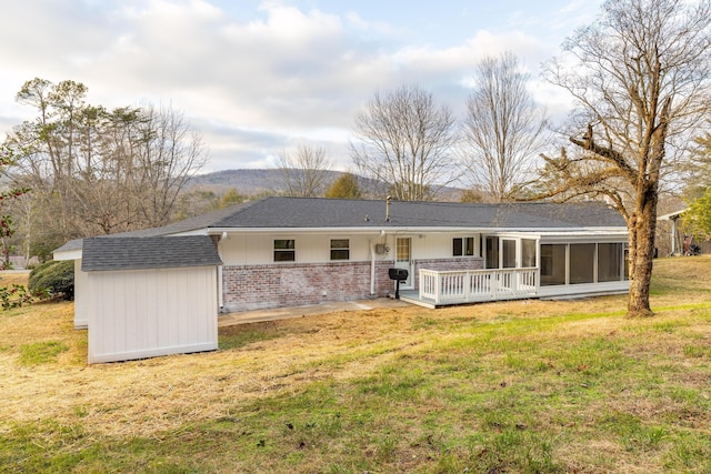 rear view of house with a yard, a wooden deck, and a sunroom