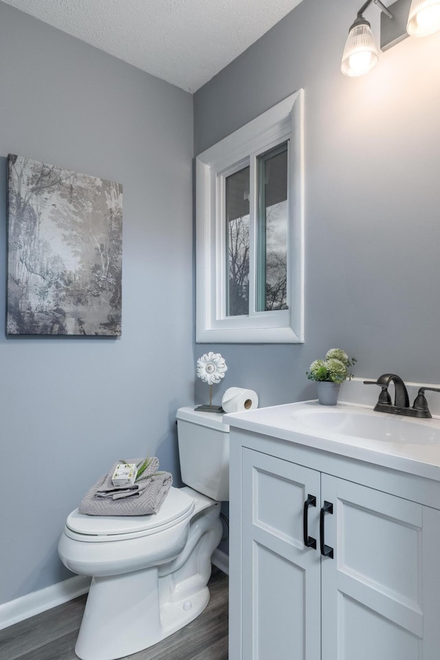 bathroom with hardwood / wood-style floors, vanity, a textured ceiling, and toilet