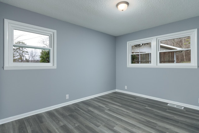 unfurnished room with dark wood-type flooring and a textured ceiling