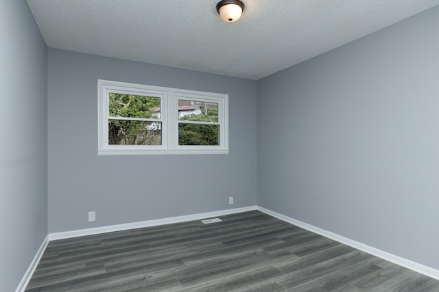 spare room with dark hardwood / wood-style floors and a textured ceiling