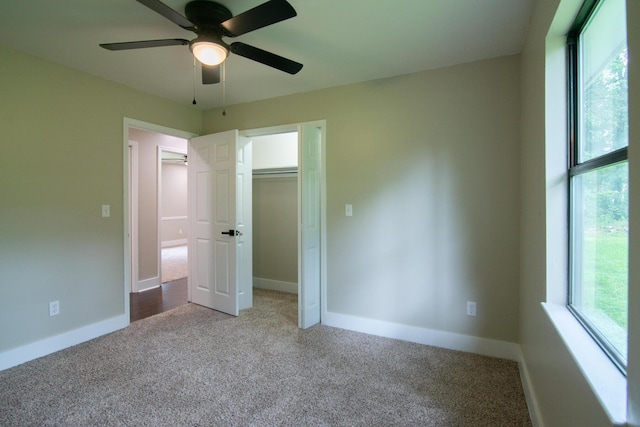 unfurnished bedroom featuring carpet, ceiling fan, a closet, and multiple windows