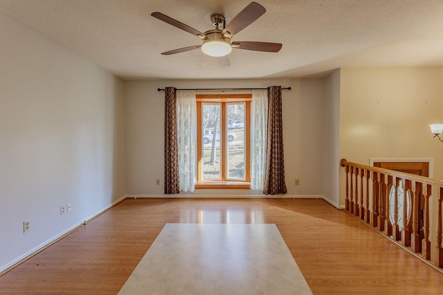 spare room featuring ceiling fan, light wood-type flooring, and a textured ceiling