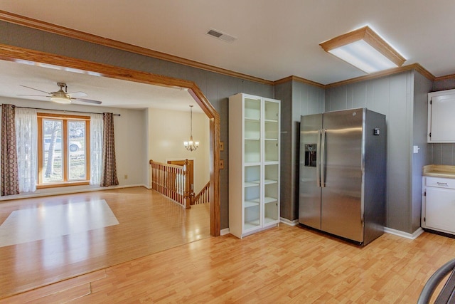 kitchen with stainless steel fridge with ice dispenser, ceiling fan with notable chandelier, light hardwood / wood-style floors, and decorative light fixtures