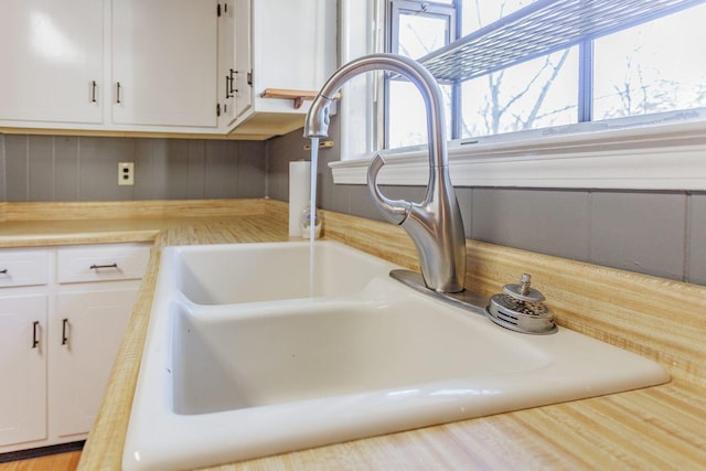 interior details featuring white cabinetry and sink