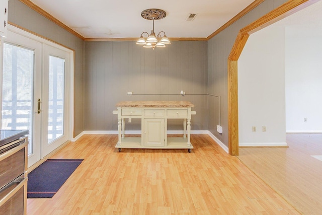 unfurnished dining area with a wealth of natural light, crown molding, french doors, and light wood-type flooring