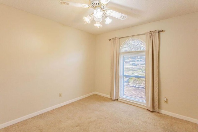 empty room featuring ceiling fan, light colored carpet, and a textured ceiling