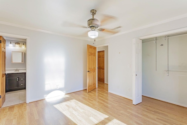 unfurnished bedroom featuring light wood-type flooring, ceiling fan, sink, connected bathroom, and a closet