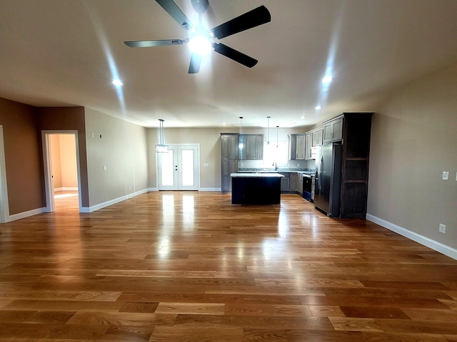 kitchen featuring stainless steel refrigerator with ice dispenser, ceiling fan, a center island, dark hardwood / wood-style floors, and hanging light fixtures