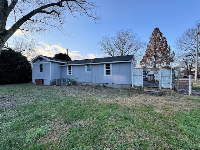 back of property featuring central AC and a lawn