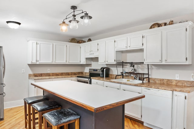 kitchen featuring appliances with stainless steel finishes, light wood-type flooring, sink, pendant lighting, and white cabinetry