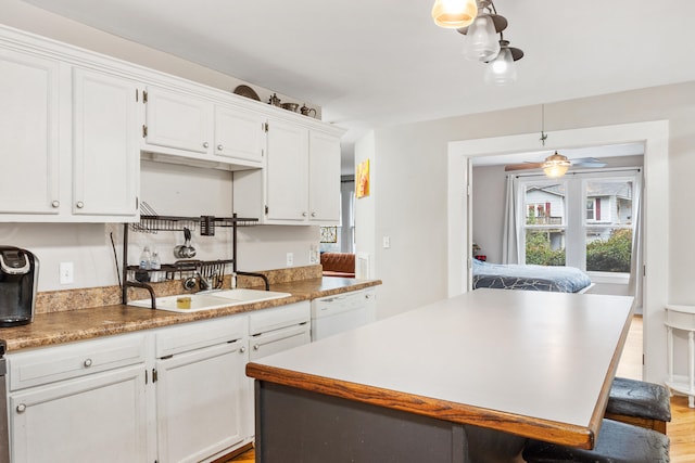 kitchen with white cabinetry, dishwasher, decorative light fixtures, and sink