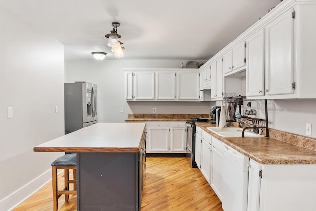 kitchen with a breakfast bar, a center island, sink, appliances with stainless steel finishes, and white cabinetry