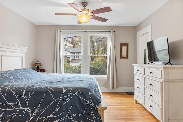 bedroom with ceiling fan, multiple windows, and light hardwood / wood-style flooring