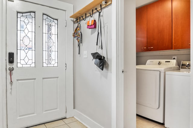 clothes washing area featuring cabinets, light tile patterned floors, and washing machine and clothes dryer